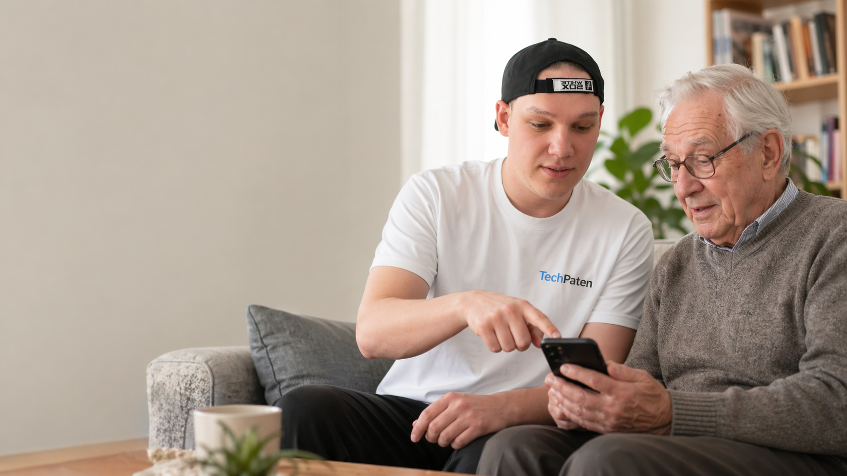 TechPate erklärt Seniorin geduldig Handy und Laptop zuhause